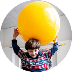 Leerexpert Capitan: jongen houdt grote gele bal op zijn hoofd_bol